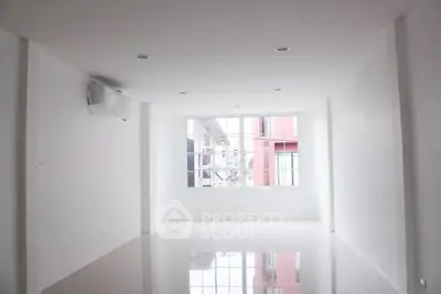 Spacious white room with large window and glossy floor, perfect for customization.