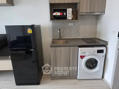 Modern compact kitchen with appliances including fridge, microwave, and washing machine.