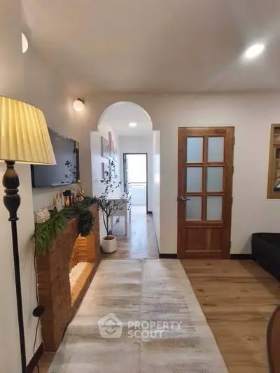 Charming living room with cozy decor and wooden accents, leading to a bright hallway.