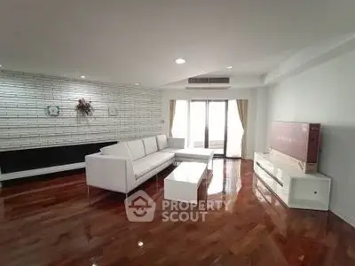 Spacious modern living room with sleek white furniture and polished wooden floors.