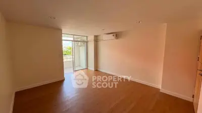 Spacious empty room with wooden flooring and balcony access, ideal for customization.
