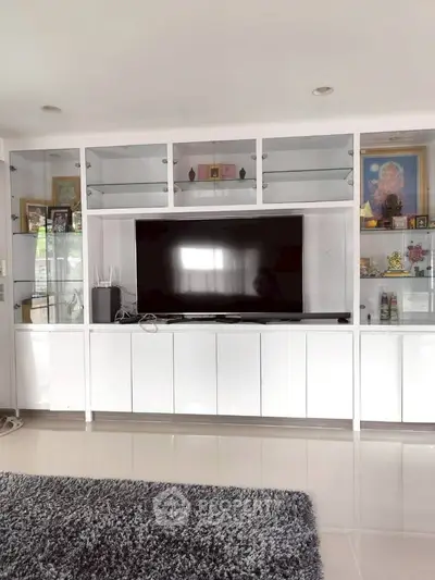 Spacious living room with modern entertainment center and sleek white cabinetry.
