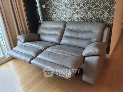 Luxurious leather recliner sofa in elegant living room with stylish wallpaper and wooden flooring.