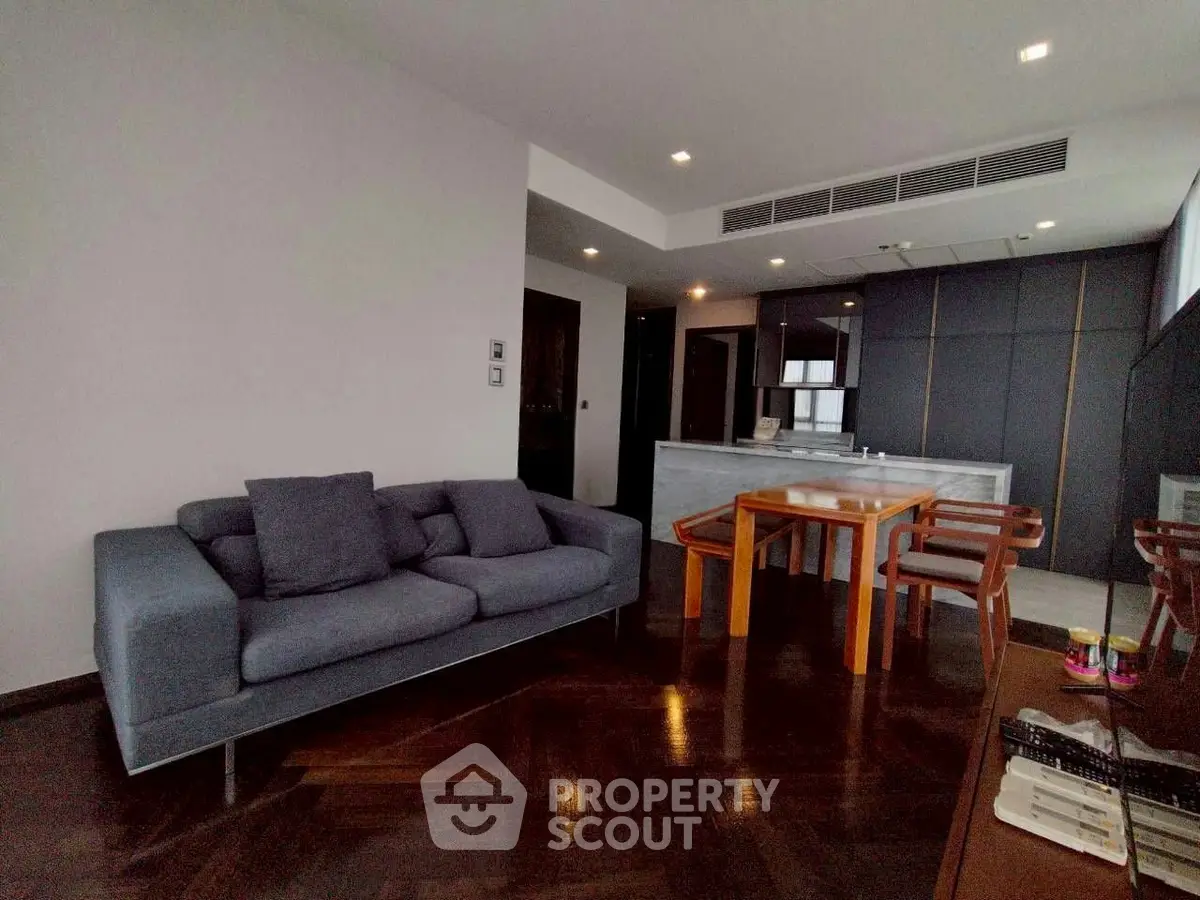 Modern living room with sleek furniture and open kitchen layout in luxury apartment.