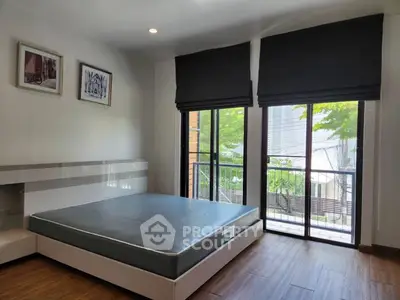 Spacious bedroom with large windows and modern decor, featuring a serene view of greenery.