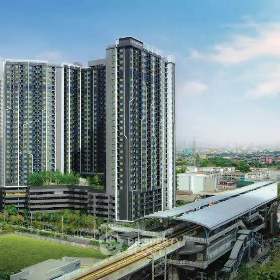 Modern high-rise residential building with cityscape view and nearby transit station.
