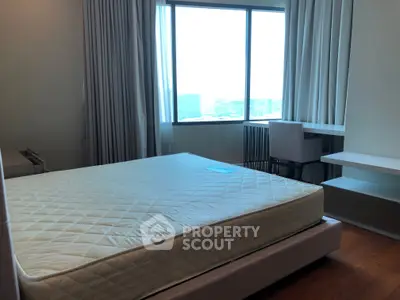 Spacious bedroom with large window offering city views, featuring a comfortable bed and modern furnishings.