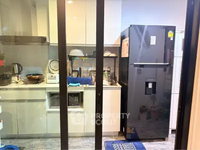 Modern kitchen with sleek appliances and glass sliding doors, featuring a spacious fridge and stylish cabinetry.