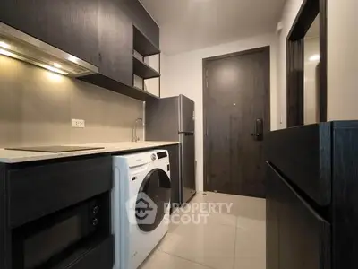 Modern kitchen with sleek cabinetry, washing machine, and stainless steel appliances in a compact layout.