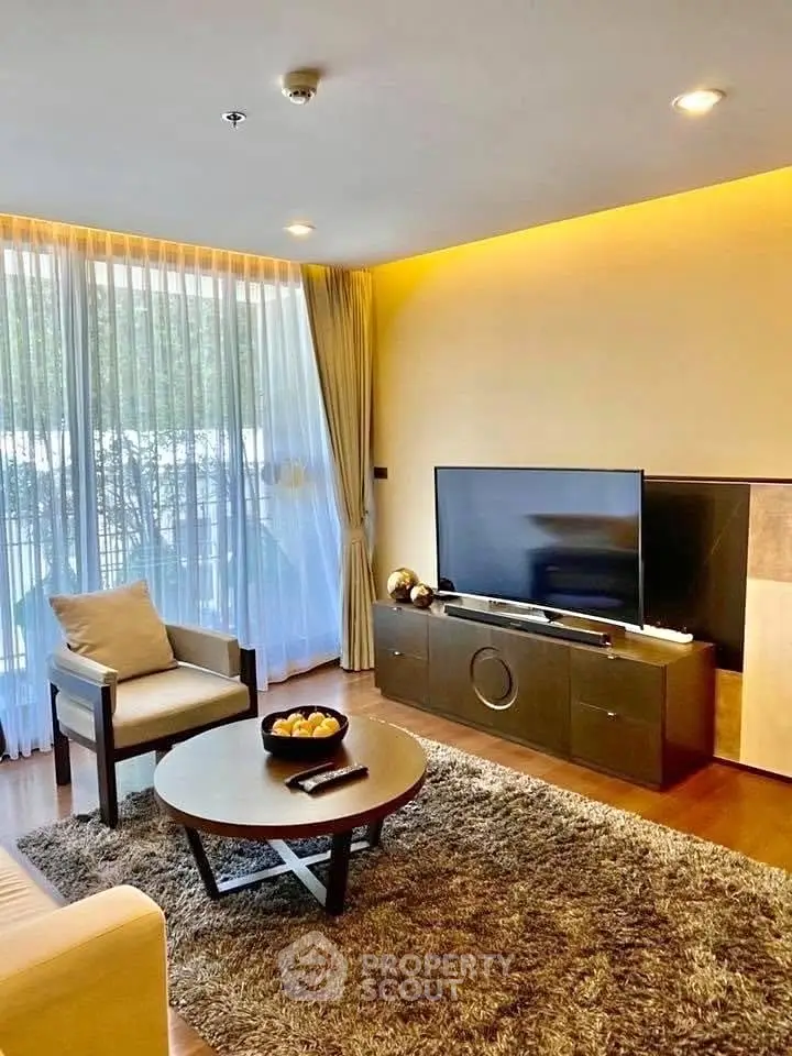 Modern living room with large window, cozy seating, and stylish decor in a bright apartment.