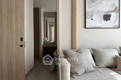 Modern living room with neutral tones and stylish decor, featuring a cozy sofa and abstract wall art.