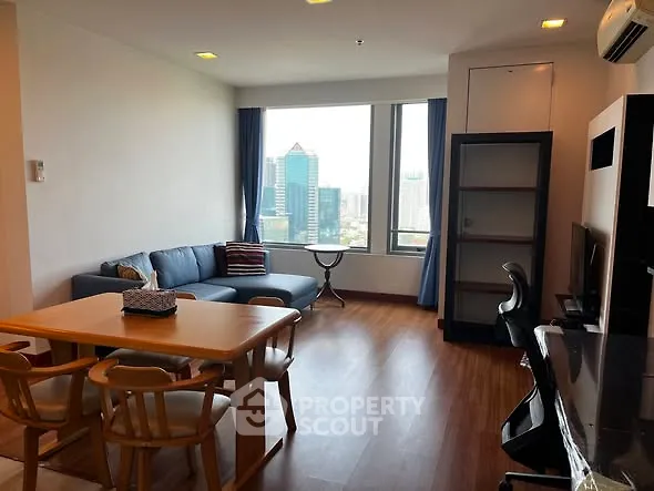 Spacious living room with city view, modern furniture, and wooden flooring in a high-rise apartment.