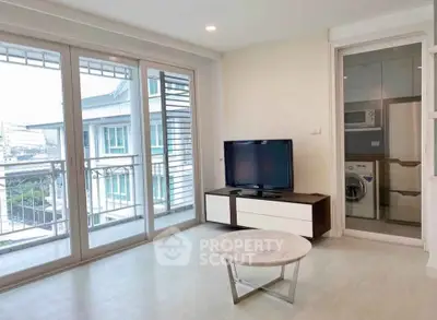 Modern living room with large windows and adjacent laundry area in a stylish apartment.