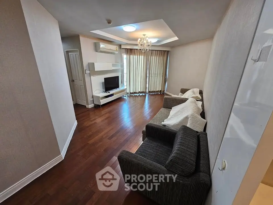 Spacious living room with hardwood floors, modern lighting, and cozy seating area.