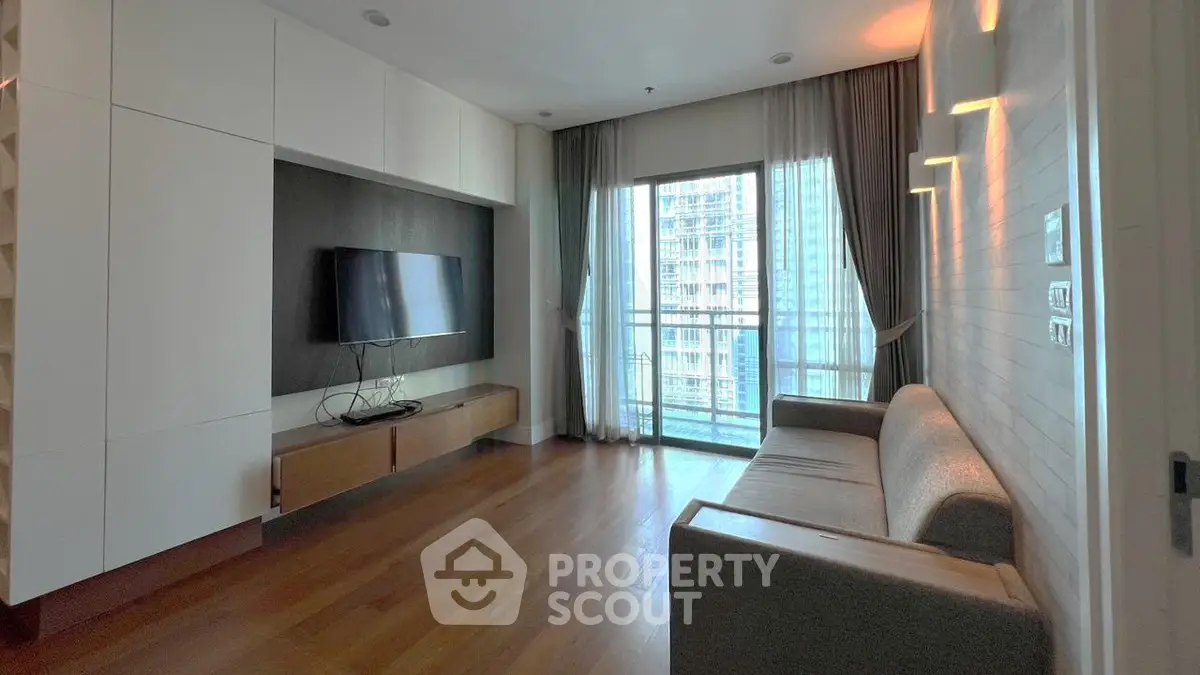 Modern living room with large window and sleek furniture in high-rise apartment.
