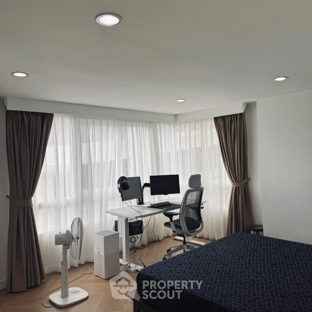 Modern bedroom with study area featuring sleek desk and ergonomic chair by large windows.