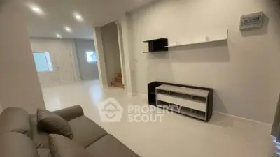 Modern living room with sleek furniture and minimalist design, featuring neutral tones and ample lighting.