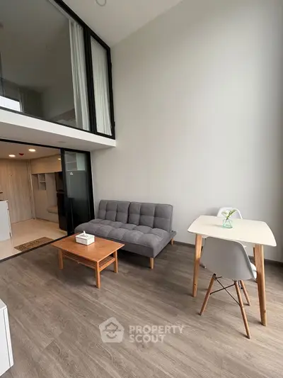 Modern loft-style living room with high ceiling and minimalist furniture