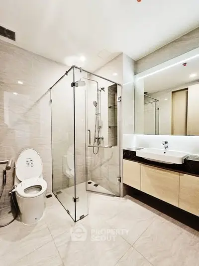Modern bathroom with glass shower and sleek vanity in luxury apartment.