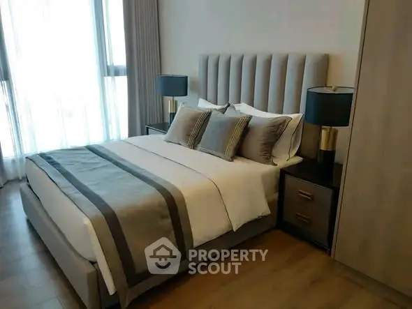 Luxurious bedroom with elegant decor and natural light, featuring a plush bed and stylish bedside lamps.