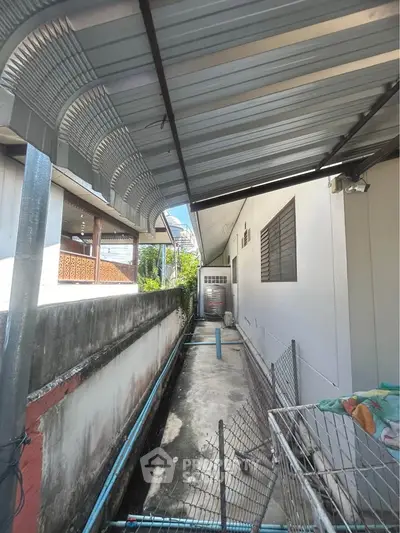 Narrow exterior side alley with metal roof and utility area