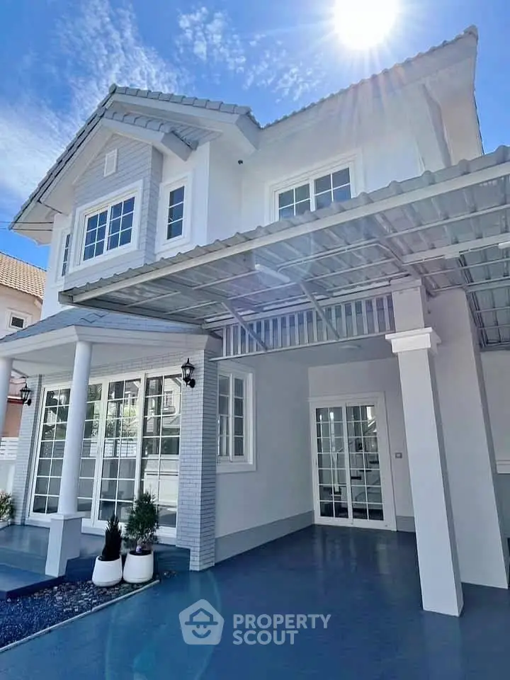 Stunning two-story house with modern design and spacious driveway under a clear blue sky.