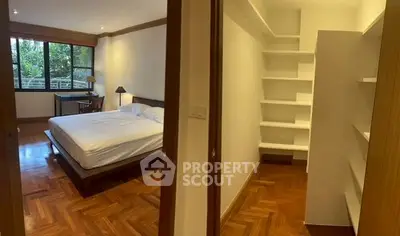 Spacious bedroom with wooden flooring and built-in shelves, ideal for comfort and storage.