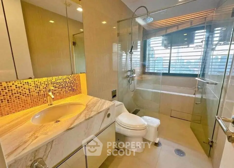 Luxurious bathroom with marble sink and modern shower in high-end apartment.