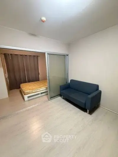 Modern apartment with cozy living room and sliding door to bedroom, featuring sleek flooring and minimalist design.