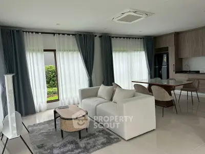 Spacious modern living room with elegant furniture and large windows offering garden views.