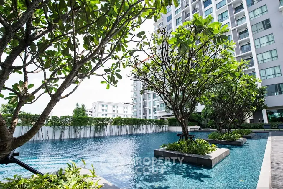 Luxurious condominium pool area with lush greenery and modern architecture.