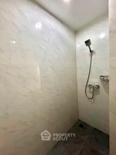 Modern bathroom with sleek marble tiles and a minimalist shower design.