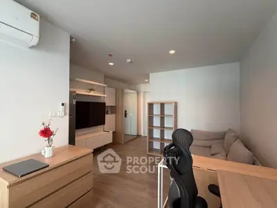 Modern living room with sleek furniture and cozy workspace in a stylish apartment.