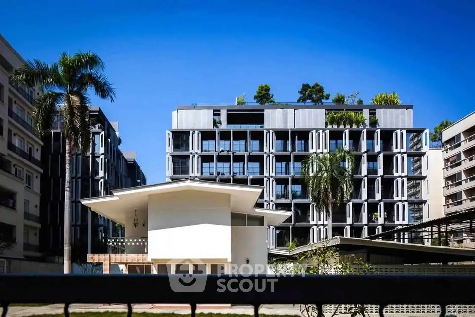 Modern apartment building with unique facade and lush greenery in urban setting.