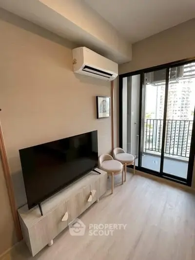 Modern living room with balcony view, featuring sleek TV setup and air conditioning.