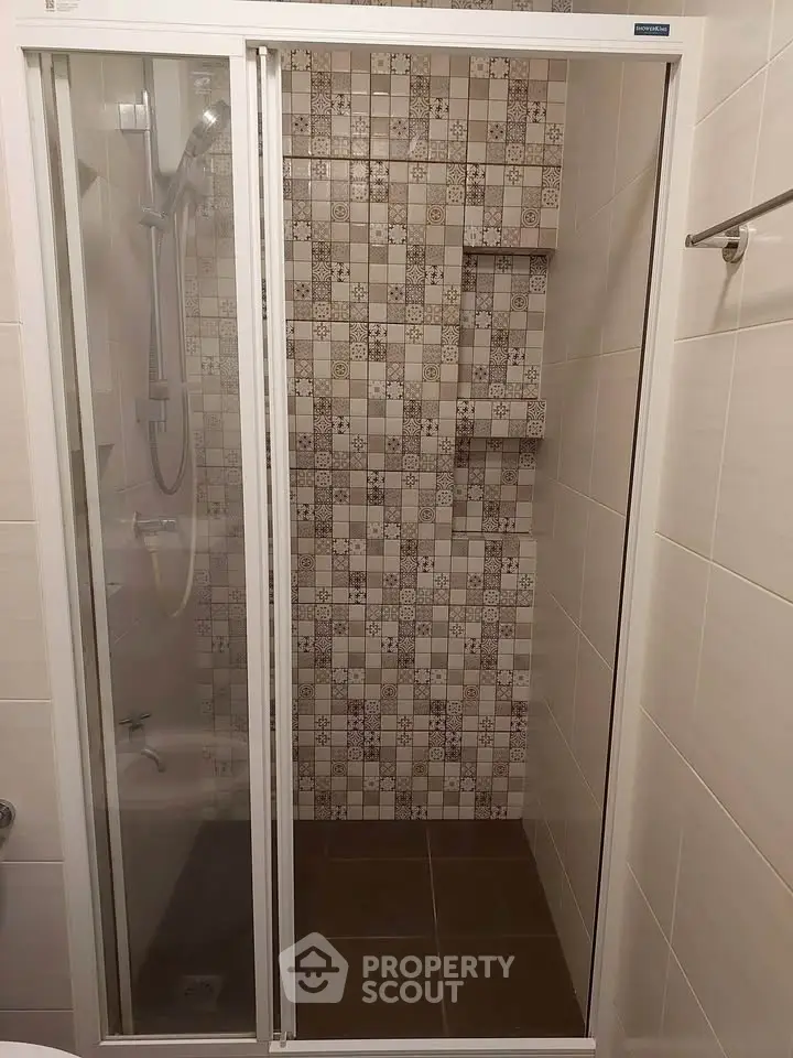 Modern bathroom with stylish tiled shower and glass door enclosure.