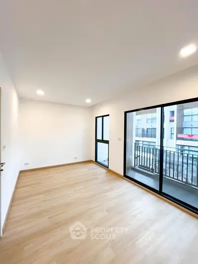 Spacious empty room with large windows and balcony access in modern apartment.