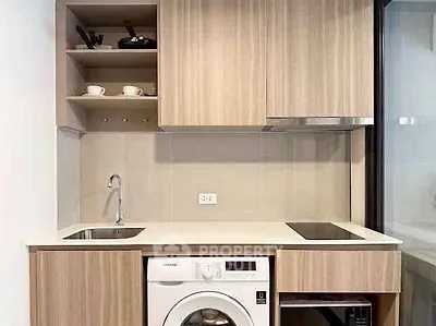 Modern compact kitchen with integrated washing machine and sleek wooden cabinets.