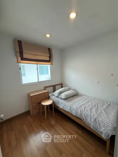 Cozy single bedroom with wooden flooring and natural light