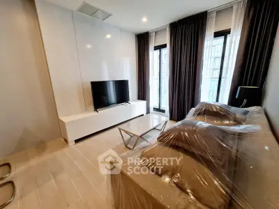 Modern living room with sleek TV setup and floor-to-ceiling windows in a stylish apartment.