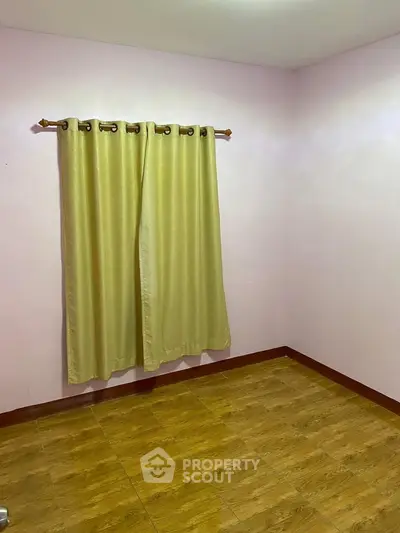 Spacious empty room with wooden flooring and yellow curtains, perfect for customization.