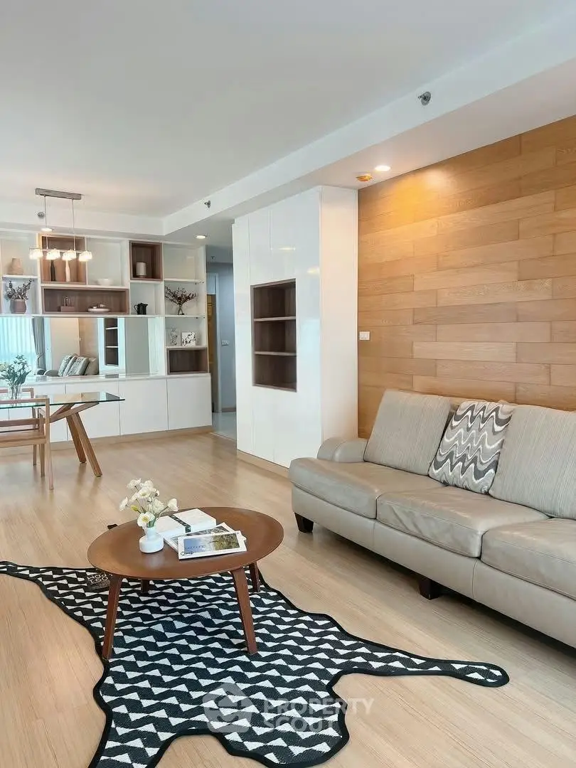 Modern living room with stylish decor and open dining area, featuring wood accents and contemporary furniture.