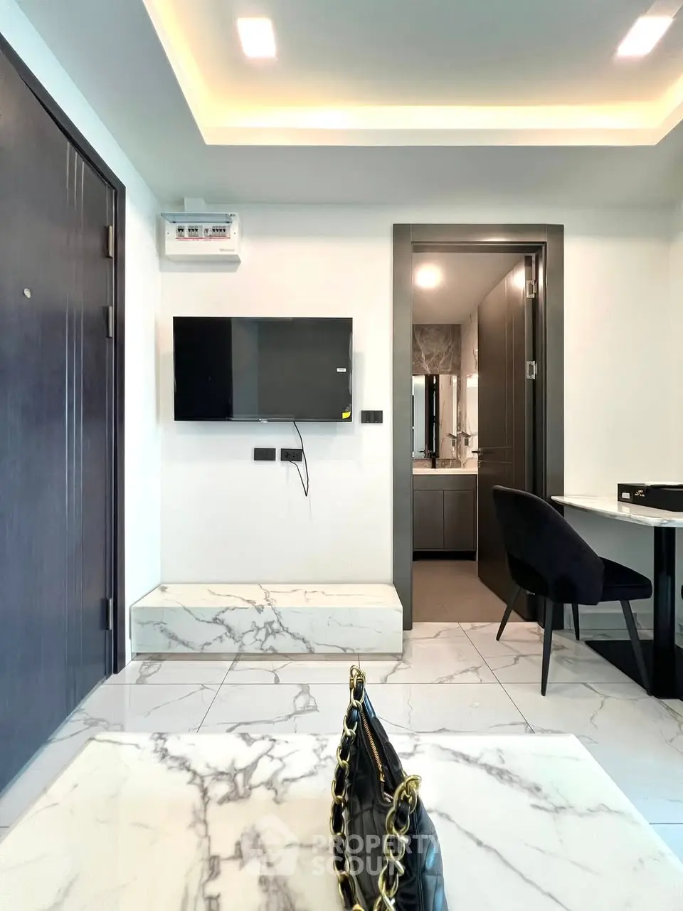 Modern interior with marble flooring and sleek furniture, featuring a wall-mounted TV and stylish decor.
