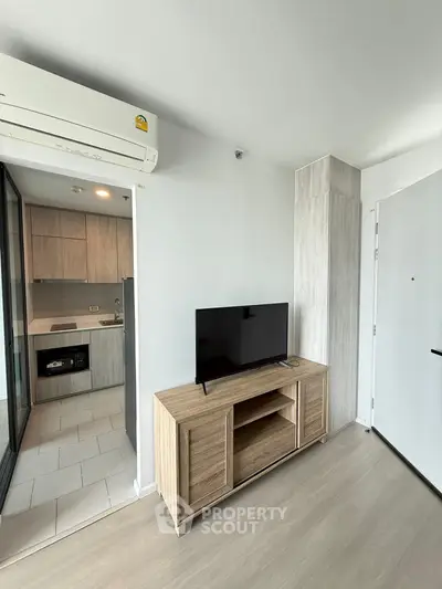 Modern apartment interior with sleek kitchen and stylish living area featuring a TV and air conditioning.