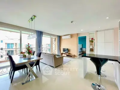Spacious modern living room with open kitchen and dining area, featuring elegant decor and ample natural light.