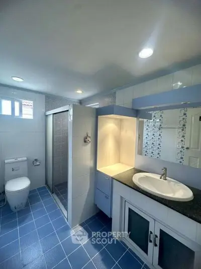 Modern bathroom with blue tiles and sleek fixtures, featuring a spacious shower and elegant vanity.