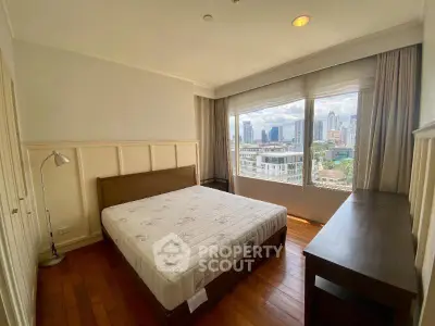 Spacious bedroom with city view and wooden flooring in modern apartment.
