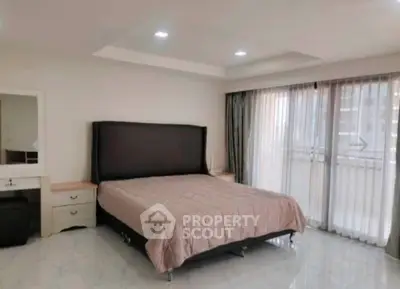 Spacious bedroom with large windows and modern decor in a luxury apartment.