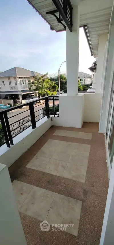 Spacious balcony with modern railing offering a serene neighborhood view, perfect for relaxation.