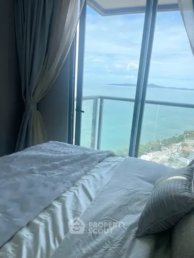 Luxurious bedroom with stunning ocean view from floor-to-ceiling windows.
